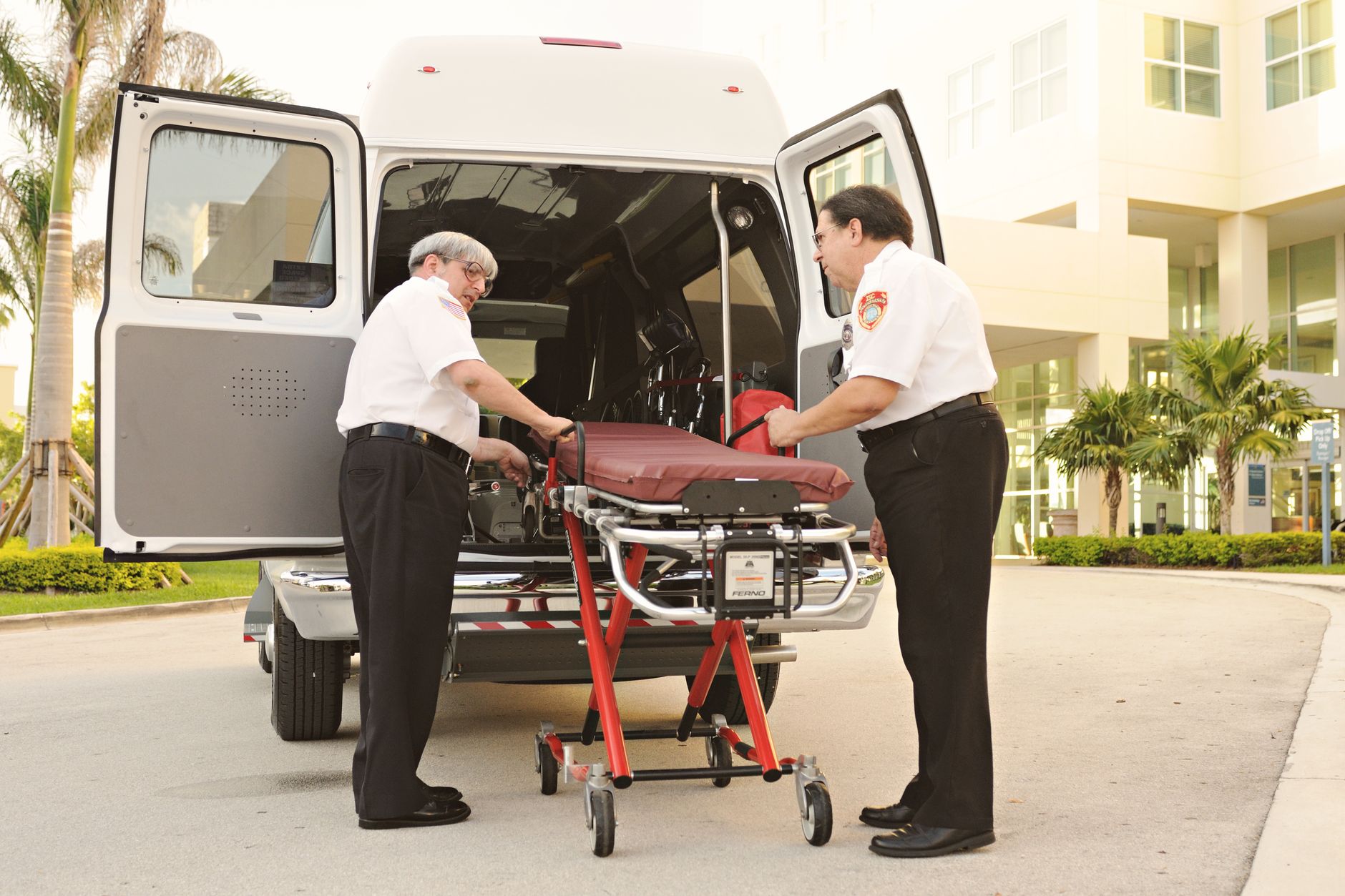 Paramedics loading a stretcher into an ambulance outside a hospital